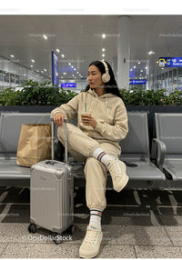 Young Woman Sitting with Luggage and Drinking Coffee at Airport