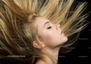 Profile of young woman with flowing blonde hair on black