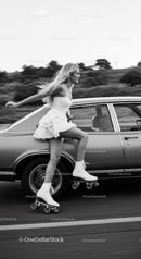 Young woman roller skating beside classic car on road
