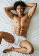 Athletic young man relaxing on bed in white underwear