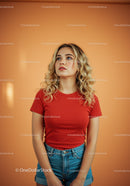 Blonde woman in red shirt looking up thoughtfully