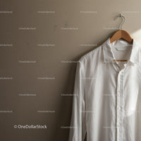 Crisp white shirt hanging on wooden hanger indoors