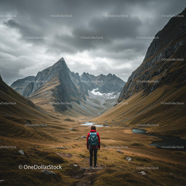 Majestic Mountain Valley with Hiker and Rocky Peaks Under Cloudy Sky