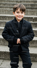 Smiling boy in black suit standing on stone steps