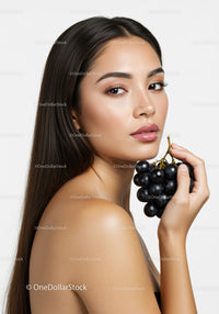 Elegant Woman with Long Dark Hair Holding Black Grapes for Beauty Portrait
