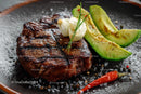 Juicy Grilled Steak with Fresh Avocado and Garlic on Rustic Board