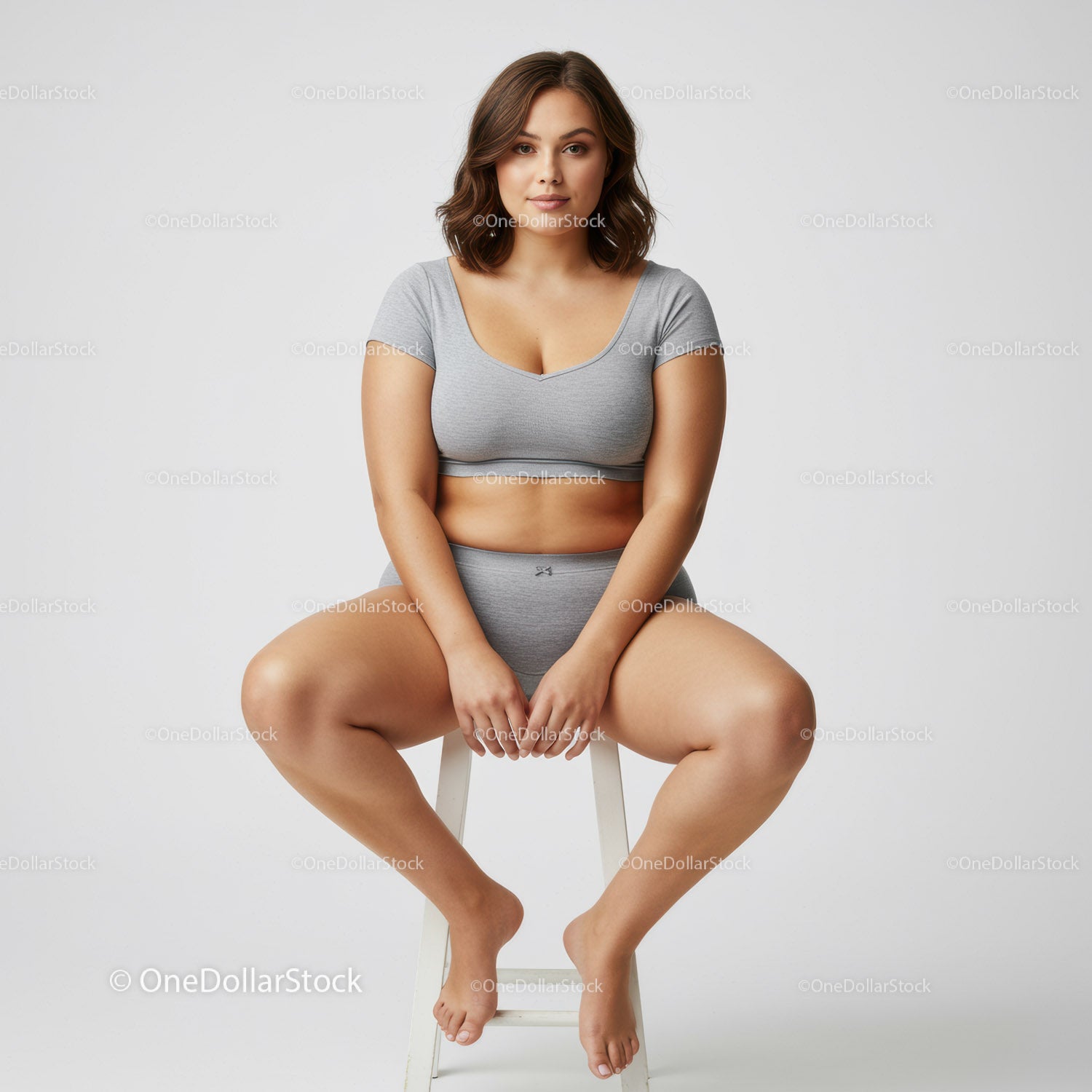 Casual Young Woman Sitting on a White Stool Wearing Gray Crop Top and Shorts