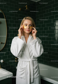 Young Woman Applying Gold Under-Eye Patches for Relaxation