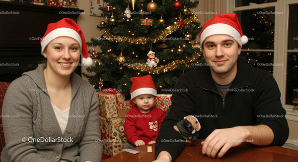 Family Wearing Santa Hats Sitting by Christmas Tree