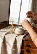 Applying facial serum on hand with natural skincare setup