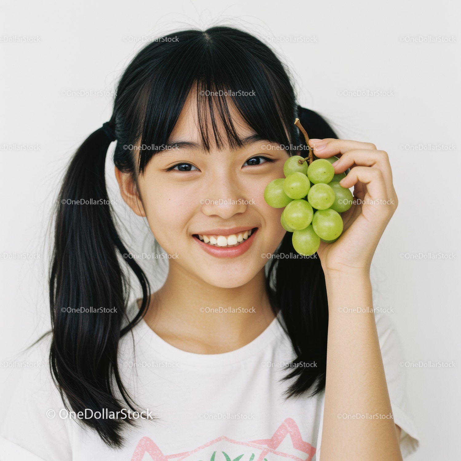 Young Woman with Green Grapes Smiling Brightly in Studio