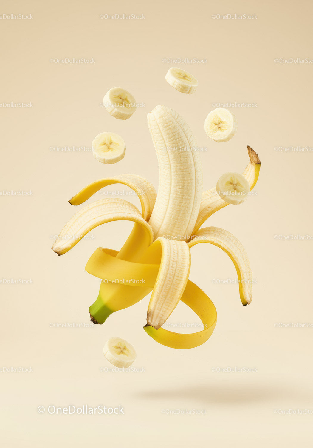 Peeled banana with floating sliced pieces on beige background