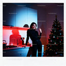 Young woman leaning in modern kitchen by Christmas tree