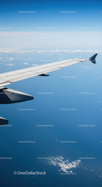 Aerial View of Airplane Wing Over Clouds in Clear Blue Sky
