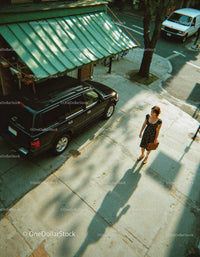 Woman Walking on City Sidewalk with Briefcase in Urban Scene