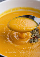 Creamy pumpkin soup with seeds and spoon close up