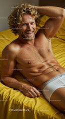 Smiling man relaxing on bed in white underwear