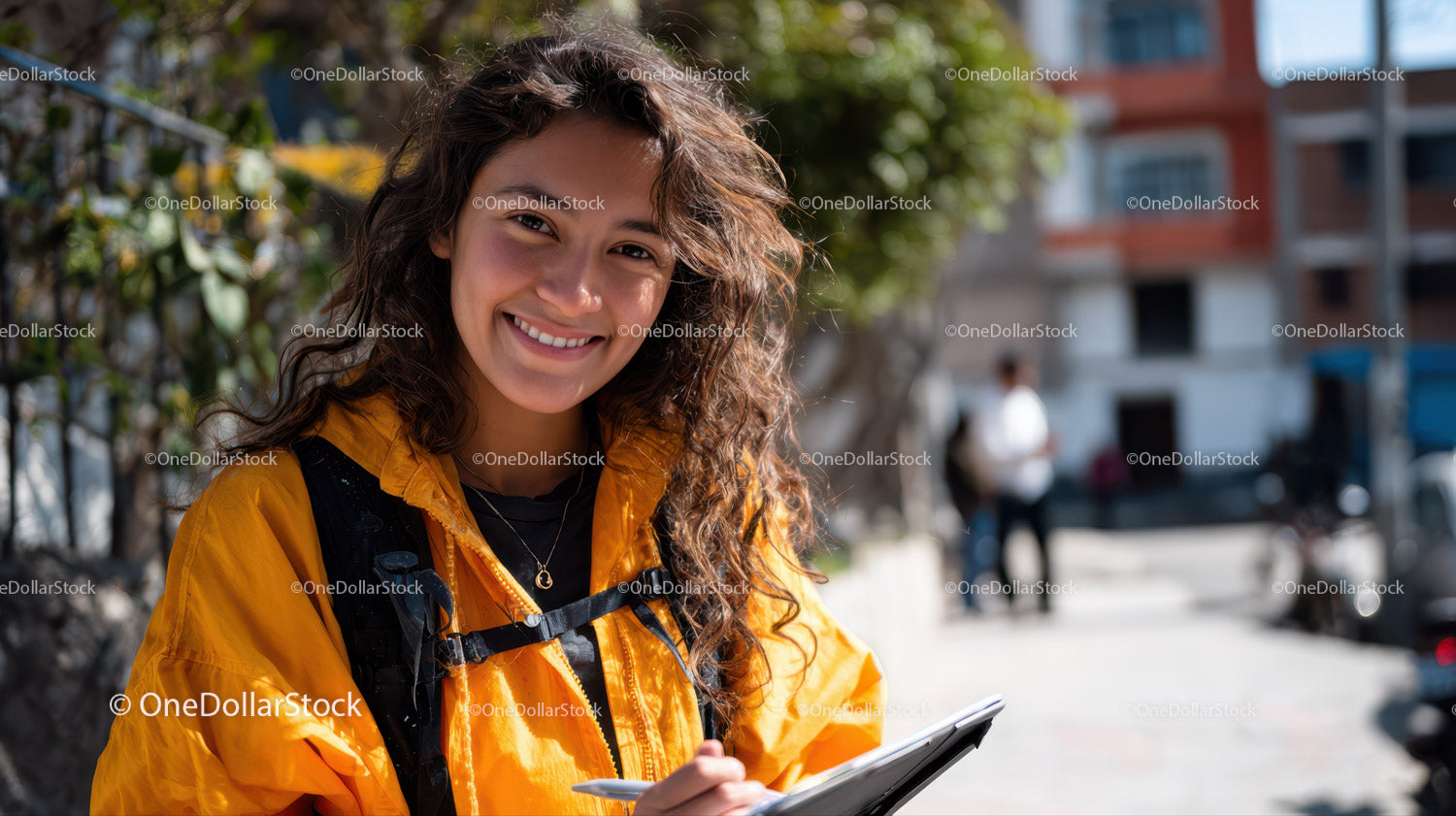 Young Woman Holding Tablet in Urban Street Scene with Greenery