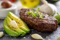 Juicy Grilled Steak with Fresh Avocado and Garlic on Rustic Board