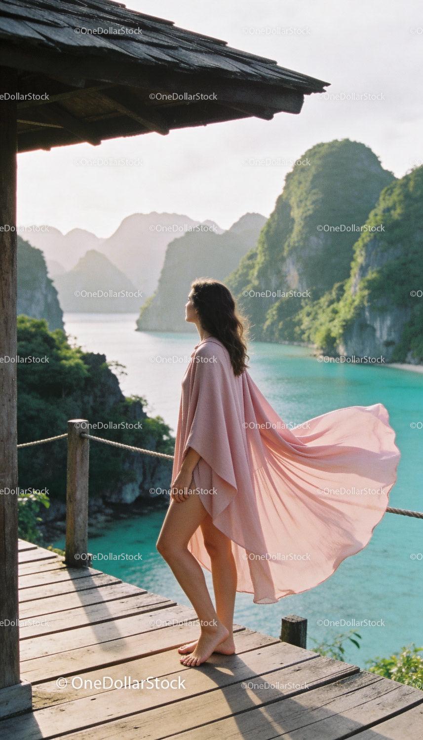 Woman in flowing pink dress overlooking turquoise lagoon