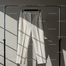 Elegant beige trousers hanging on metal rack