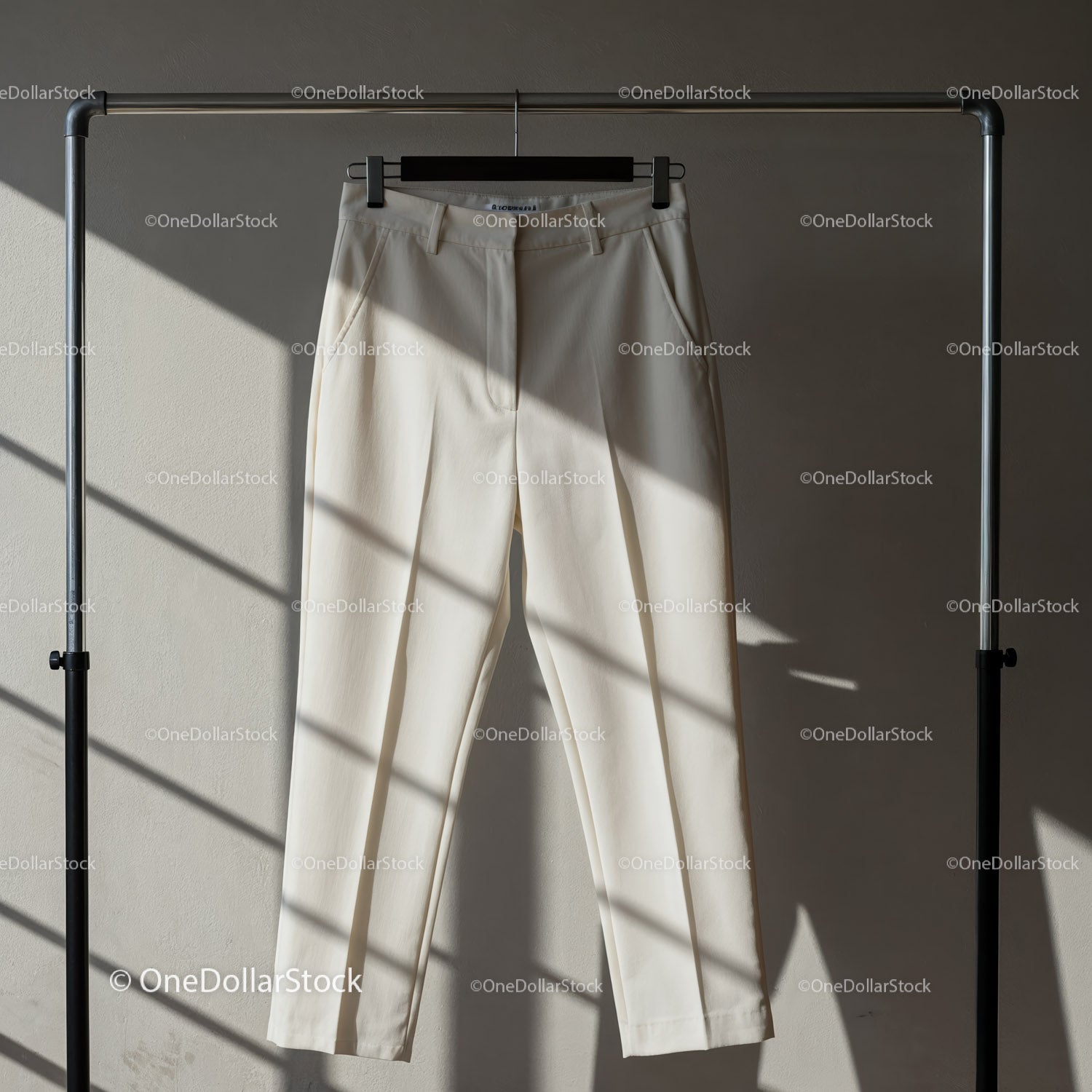 Elegant beige trousers hanging on metal rack