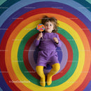 Toddler lying on colorful circular rainbow pattern floor