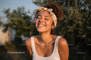 Portrait of a Smiling Young Woman with Curly Hair and Headband Outdoors