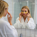 Woman Applying Eye Mask in Bathroom Mirror for Skincare Routine