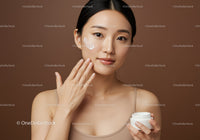 Young Woman Applying Cream for Skin Care on Brown Background