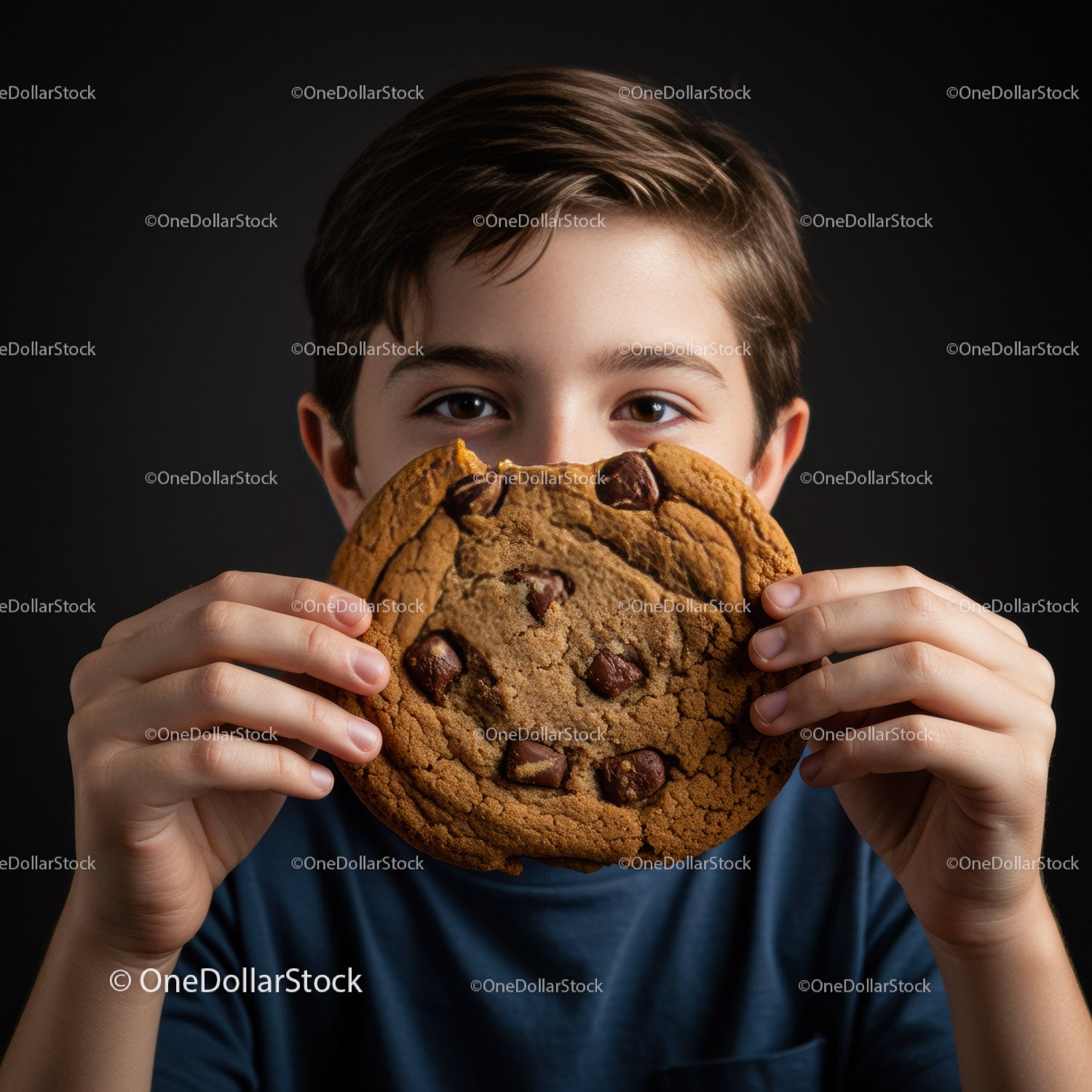 Young boy holding large chocolate chip cookie close up