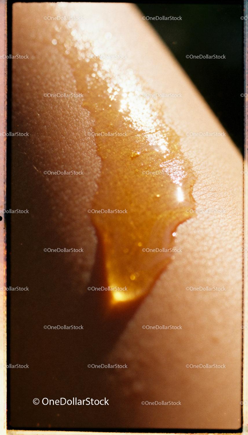Close-up of golden oil dripping on smooth skin