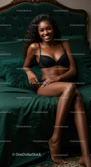 Smiling woman in black lingerie sitting on emerald bed