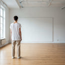 Man standing in bright empty room looking at blank wall