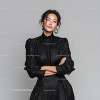 Elegant Woman in Black Dress Standing Confidently Against Grey Background