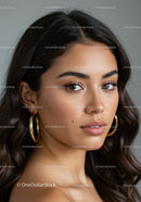 Elegant Portrait of a Young Woman with Wavy Hair and Gold Earrings