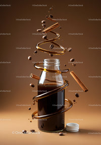 Glass Bottle of Coffee Surrounded by Floating Spices