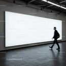 Businessman walking past large white illuminated billboard