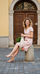Smiling young woman sitting outdoors with fresh groceries