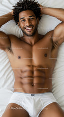 Smiling athletic man resting on bed in white underwear