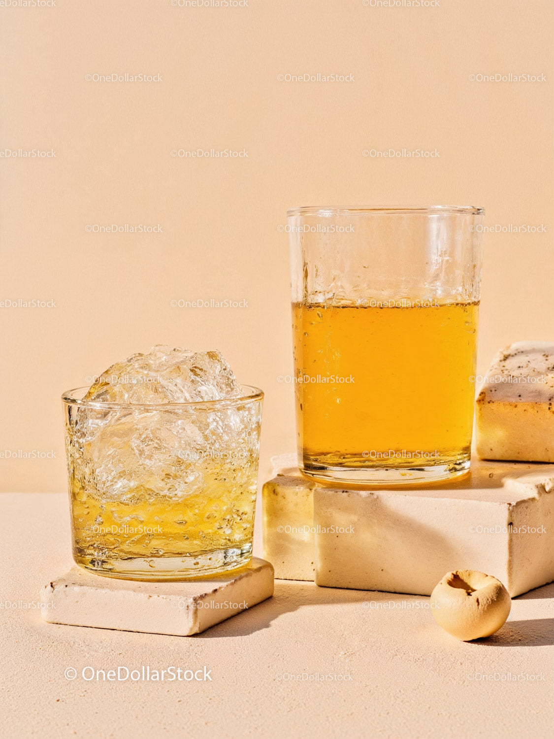 Refreshing amber drink with ice cubes on stone blocks