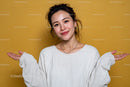 Young Woman Smiling Cheerfully in White Sweater Against Yellow Background