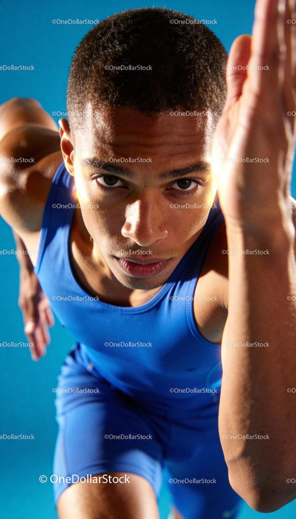 Focused young male sprinter taking off from the start line