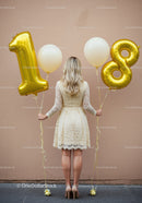 Woman holding gold balloons celebrating eighteenth birthday