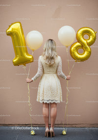 Woman holding gold balloons celebrating eighteenth birthday