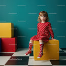 Little girl in red polka dot dress sitting on yellow cube