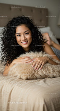 Smiling woman relaxing on bed with fluffy pillow