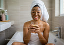 Young Woman in Bathroom Enjoying Herbal Tea and Facial Mask