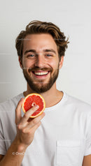 Young Man Smiling Holding Grapefruit in Bright Studio Portrait