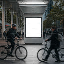 Urban commuters cycling past empty city billboard